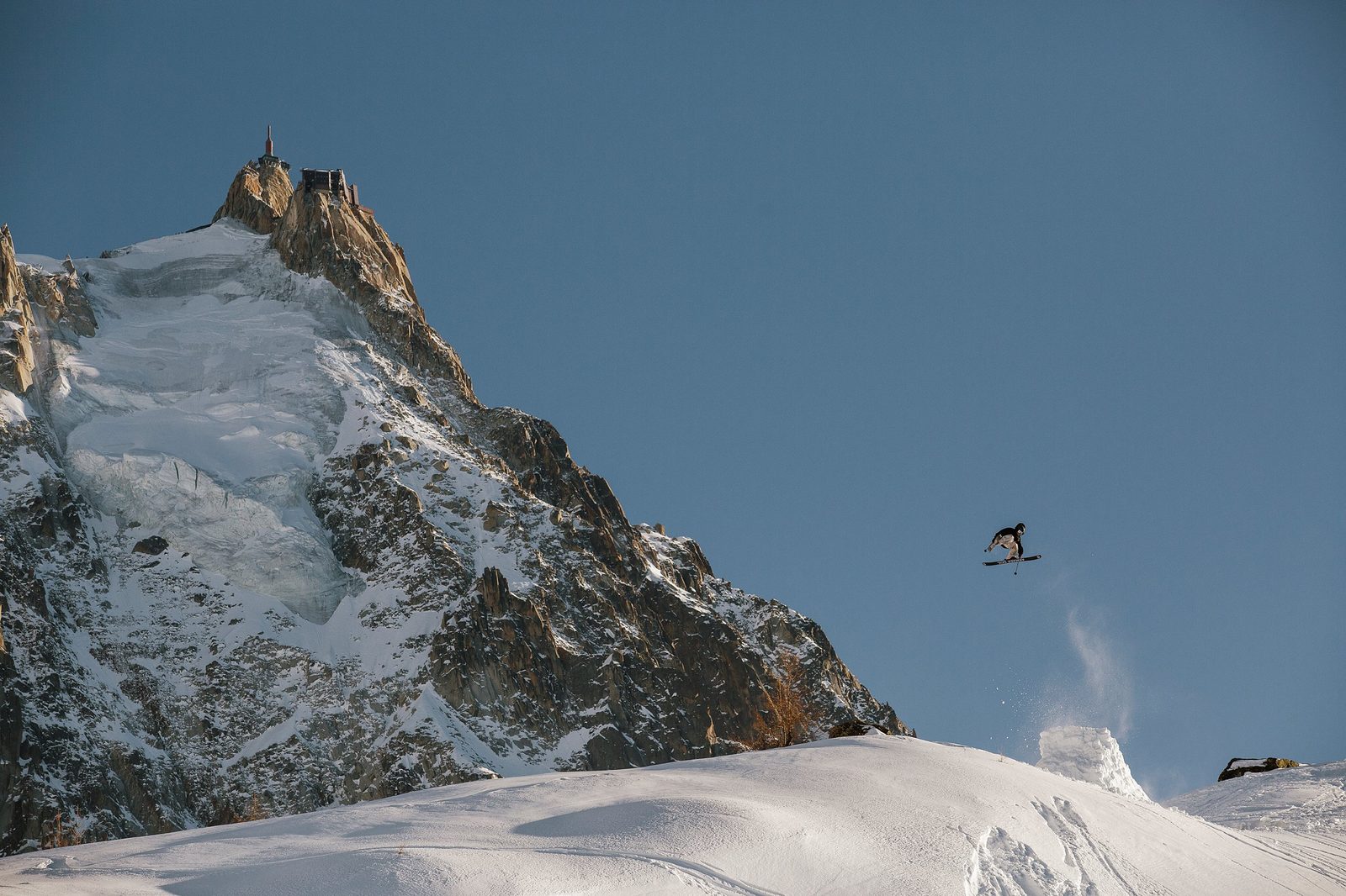 Skier in the air below Aiguille du Midi